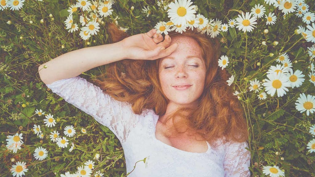 frau liegt in blumenwiese pflanzenschamanismus