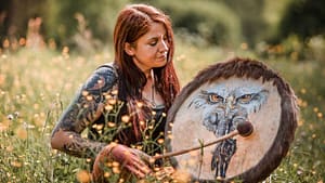 ina allard auf ihrem schamanischen weg mit einer krafttier trommel sitzt auf einer grünen wiese