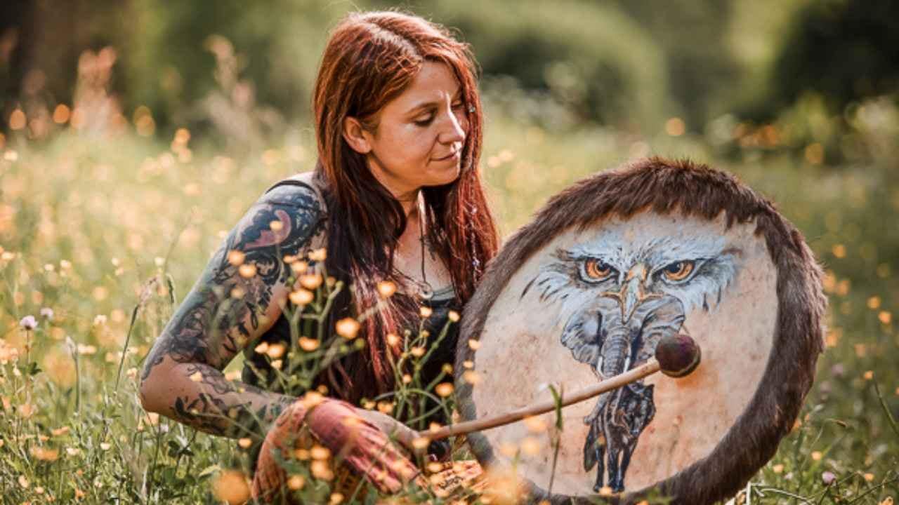 ina allard auf ihrem schamanischen weg mit einer krafttier trommel sitzt auf einer grünen wiese