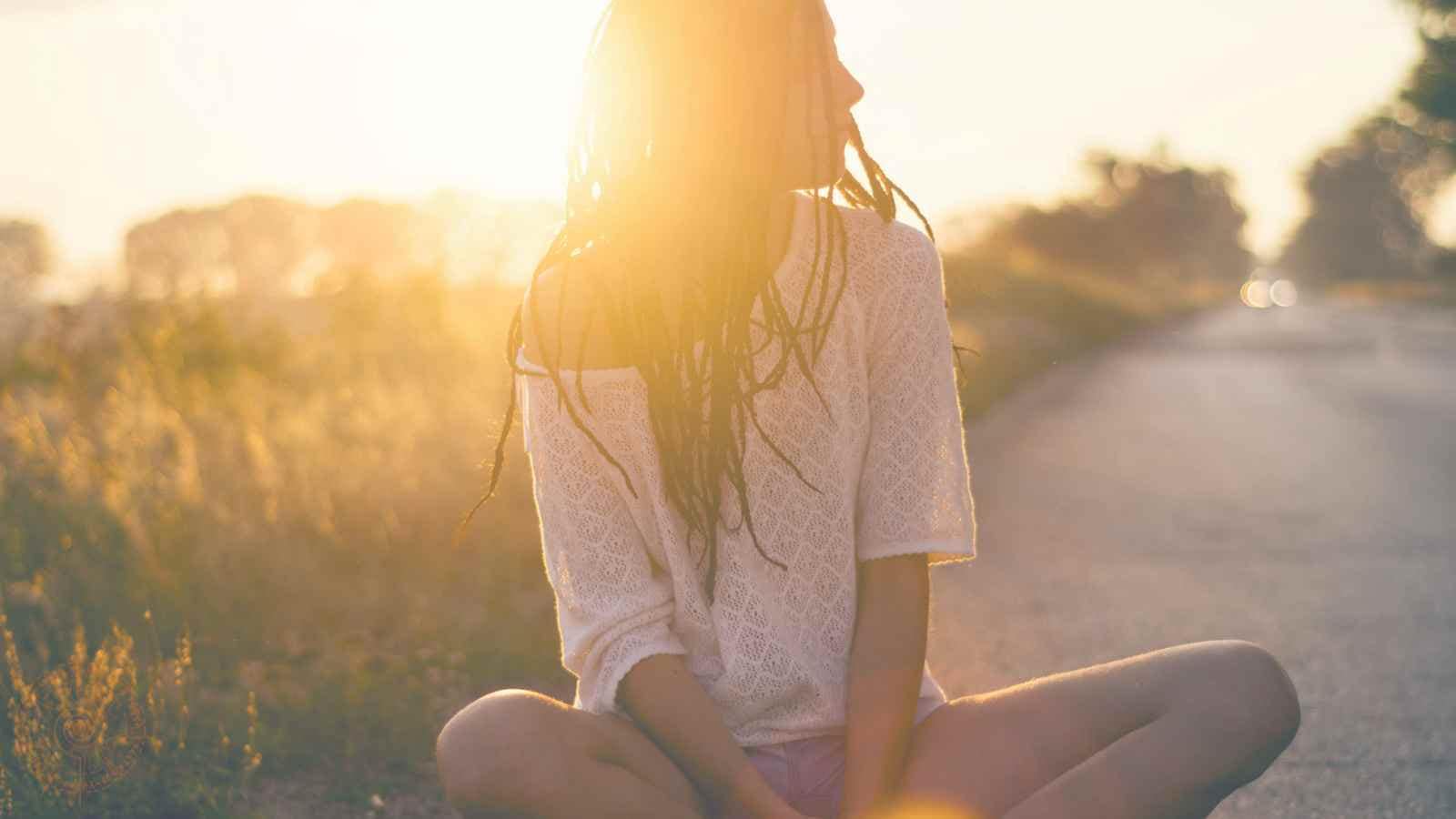 Welcher spirituelle Typ bin ich frau sitzt im sonnenuntergang auf einem weg im schneidersitz