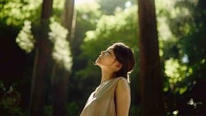 eine frau steht in der natur mit geschlossenen augen und nutz die kraft des heilens mit der natur